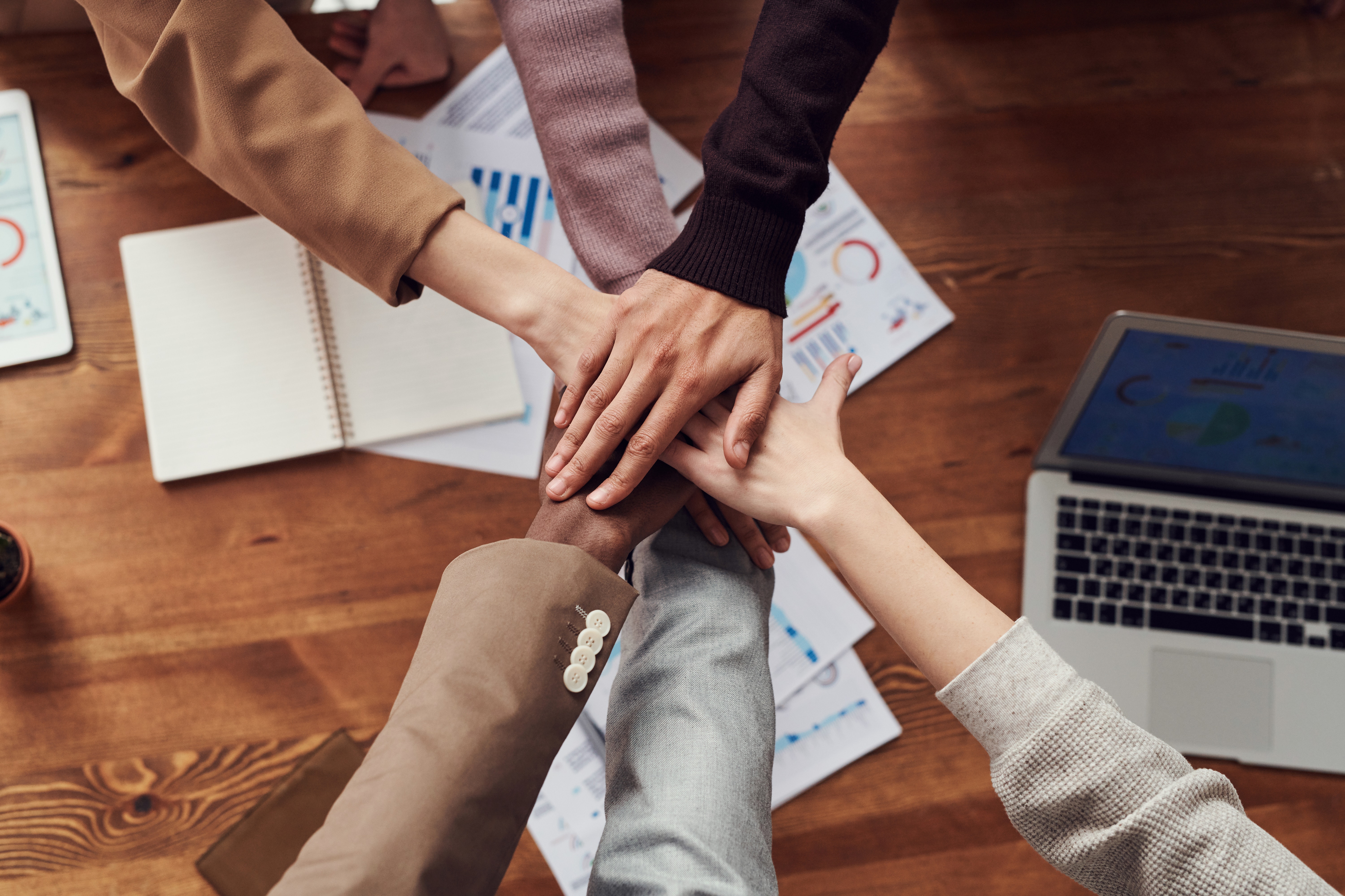 Many hands coming in together in the center of the photo to display 